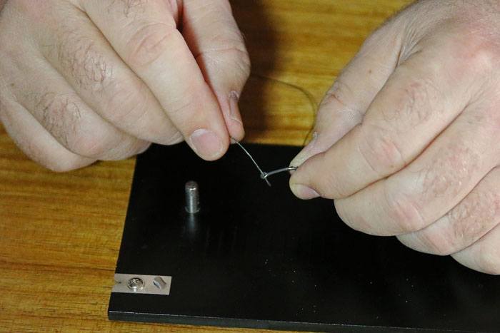7 Wikkel de lijn 2x om de haaksteel en steek de lijn van achteren door het oog van de haak en trek aan